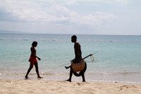 Spearfisherman and bikini clad woman walking on beach